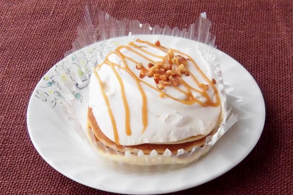 パンケーキ3枚の上にたっぷりのクリームと、線がけになったソースにナッツの飾りつけ。