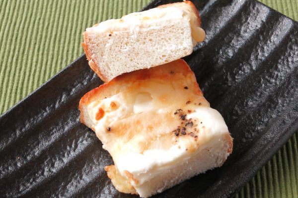 厚手のパンの上に、白いチーズフィリングが塗られています。